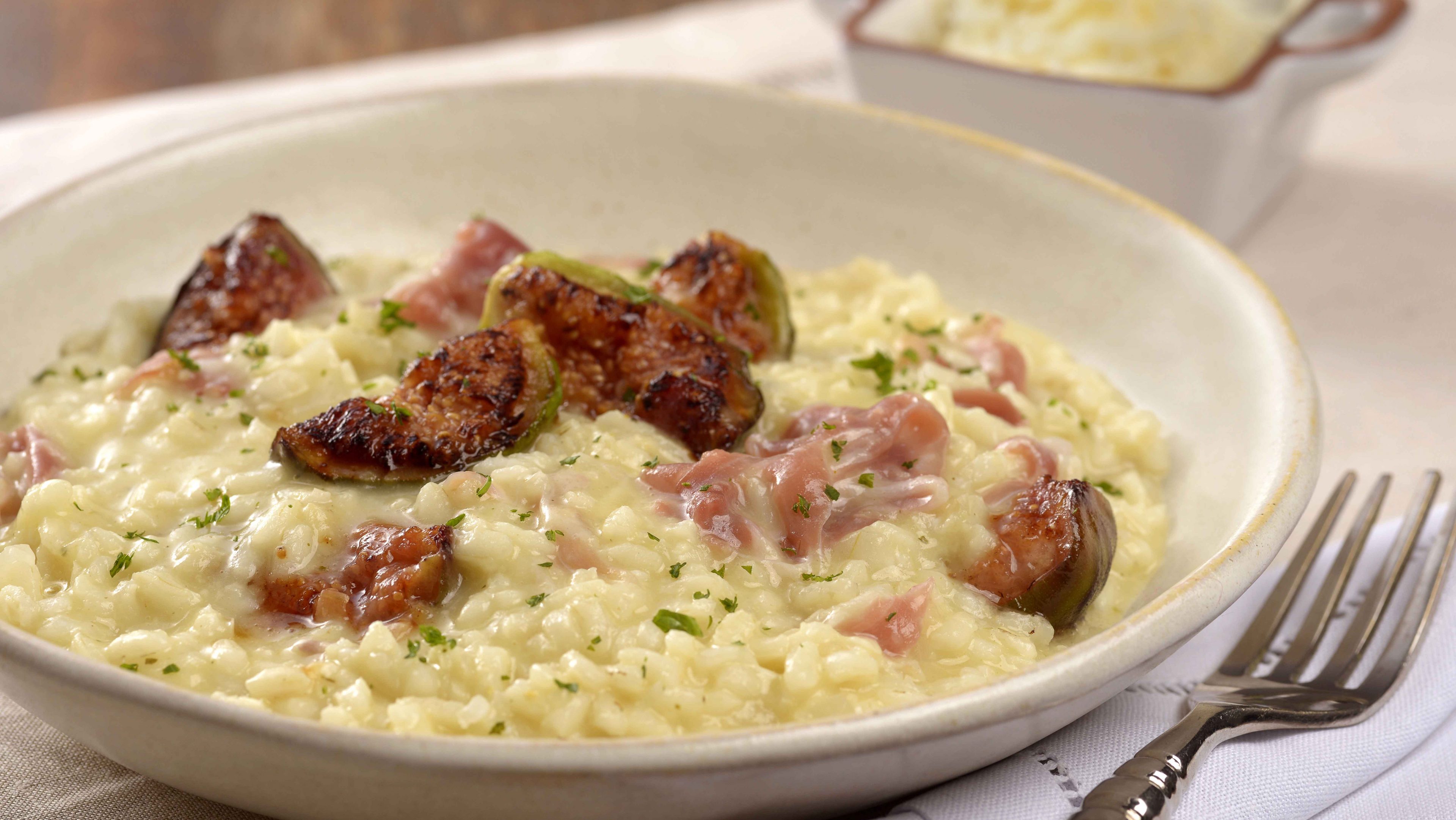 Imagem de um prato fundo com risoto e um garfo ao lado direito