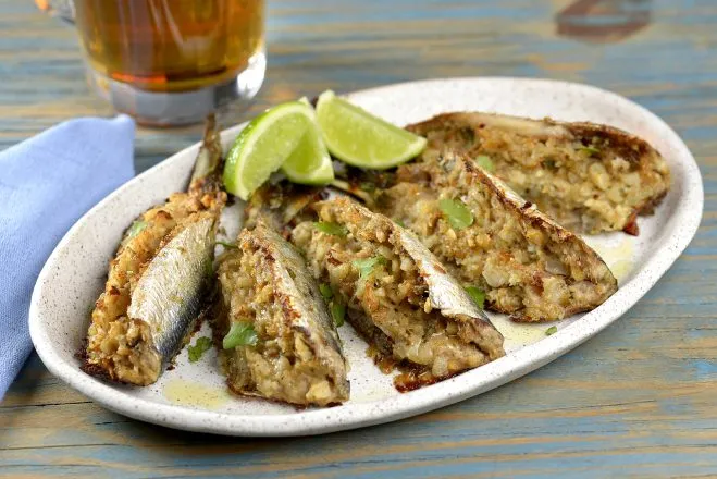 Sardinhas recheadas com rodelas de limão ao lado em um prato branco