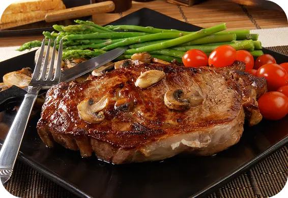 Prato com carne ao molho, tomates, aspargos e um garfo