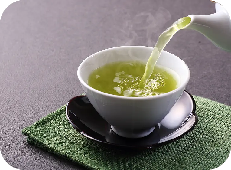 Bule colocando chá verde em uma xícara