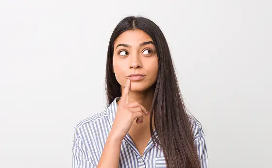 Mulher pensativa com o dedo próximo aos lábios