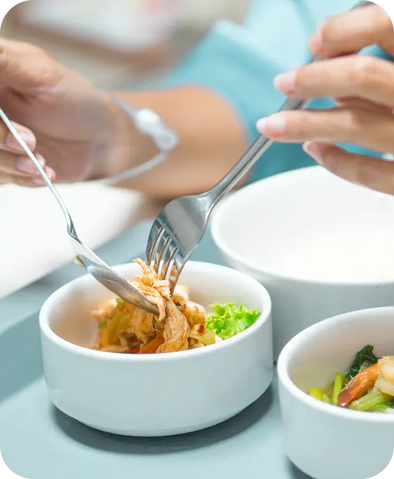 Pessoa pegando patê de uma tijela branca com colher e garfo